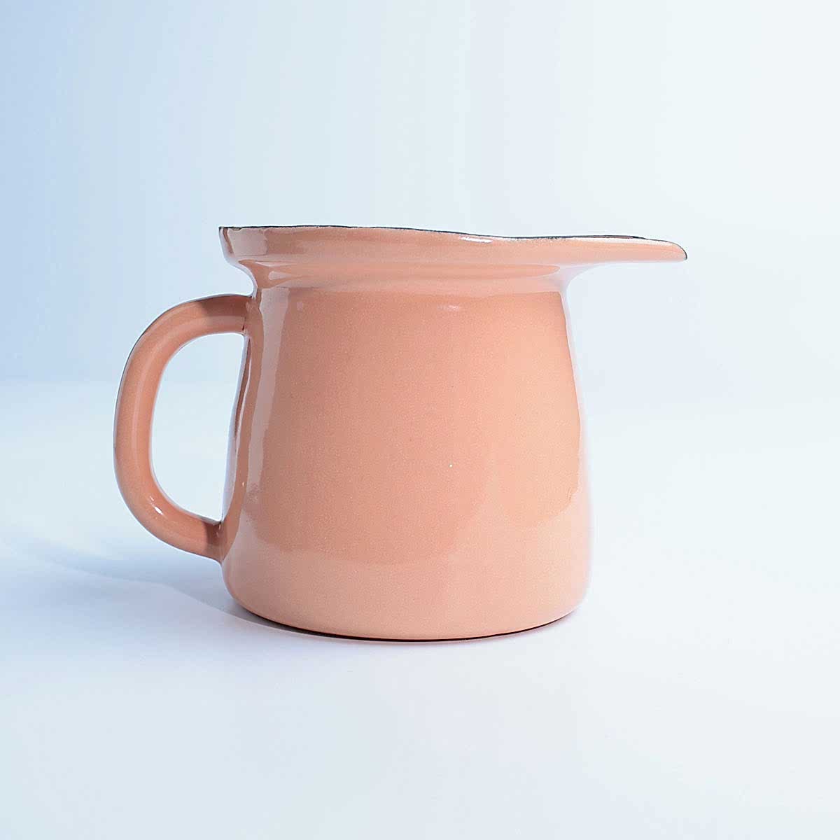 Beyaz zemin üzerinde duran, kulplu ve ağızlı, parlak yavruağzı renkte emaye sosluk.